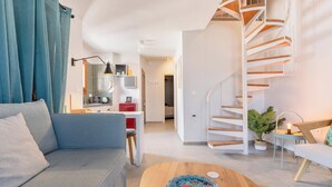 Una sala moderna con un sofá azul, una mesa de centro de madera y una escalera de caracol.