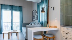 Una habitación moderna y bien iluminada con sofá, mesa de comedor y pequeña cocina.