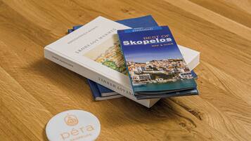 A wooden table with a book titled "Best of Skopelos" and a small white badge with the logo "pera Skopelos".