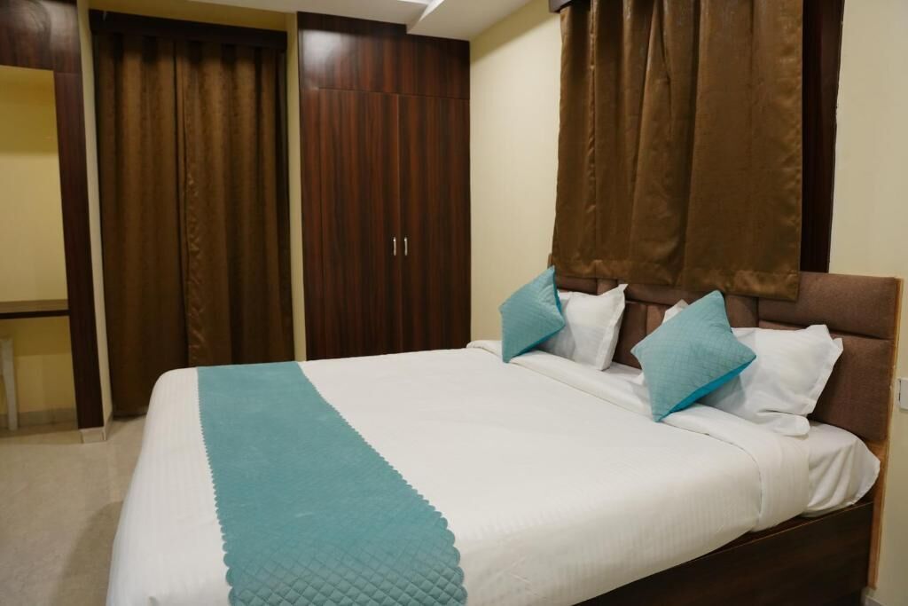 A neatly made bed with a white and teal bedspread, two pillows, and a brown headboard.