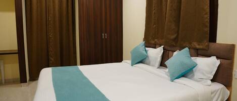 A neatly made bed with a white and teal bedspread, two pillows, and a brown headboard.