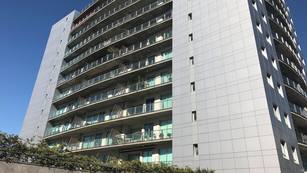 Moderni korkea kerrostalo, jossa on useita parvekkeita ja suuret ikkunat.