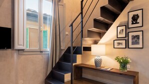 En trappa med modern design, en vägglampa och inramade tavlor.