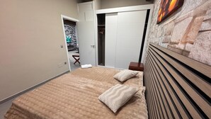 A bedroom with a large bed, a wardrobe, and a stone wall.