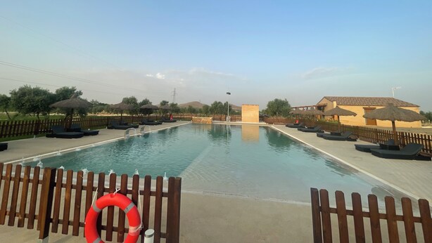 A swimming pool with a wooden fence, lounge chairs, and a lifebuoy.