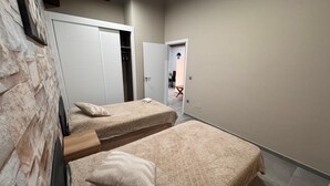 A bedroom with two beds, a stone wall, and a door leading to a bathroom.