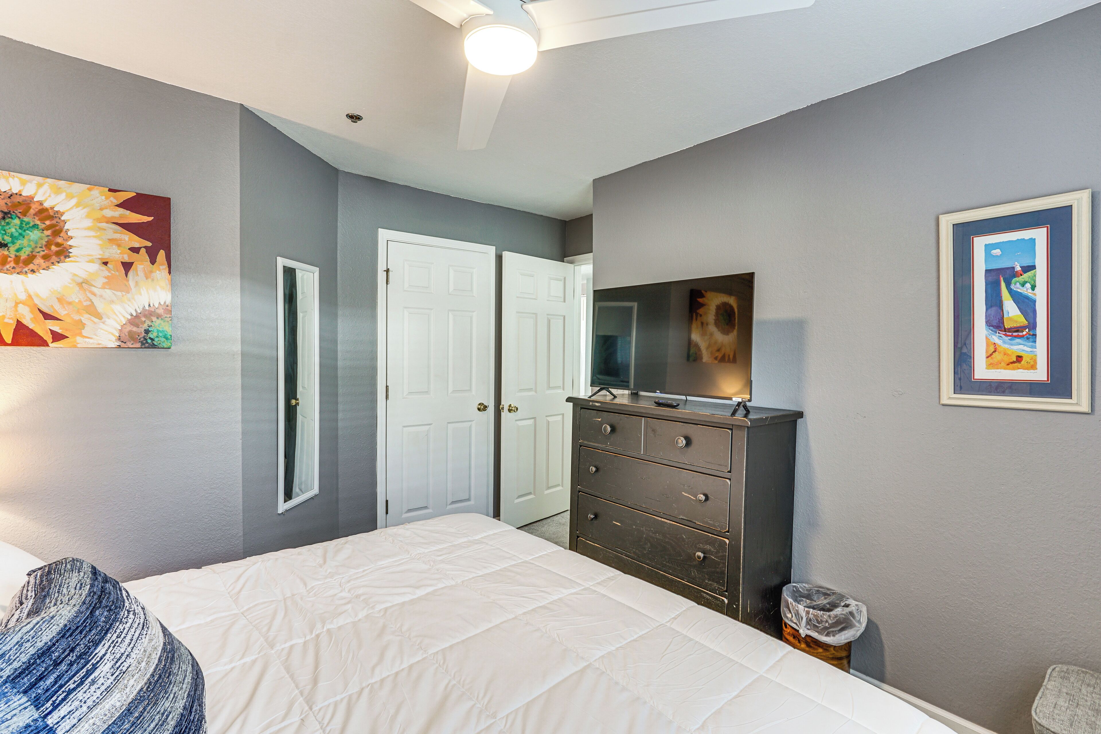 Een slaapkamer met een bed, een dressoir en kunstwerken aan de muur.