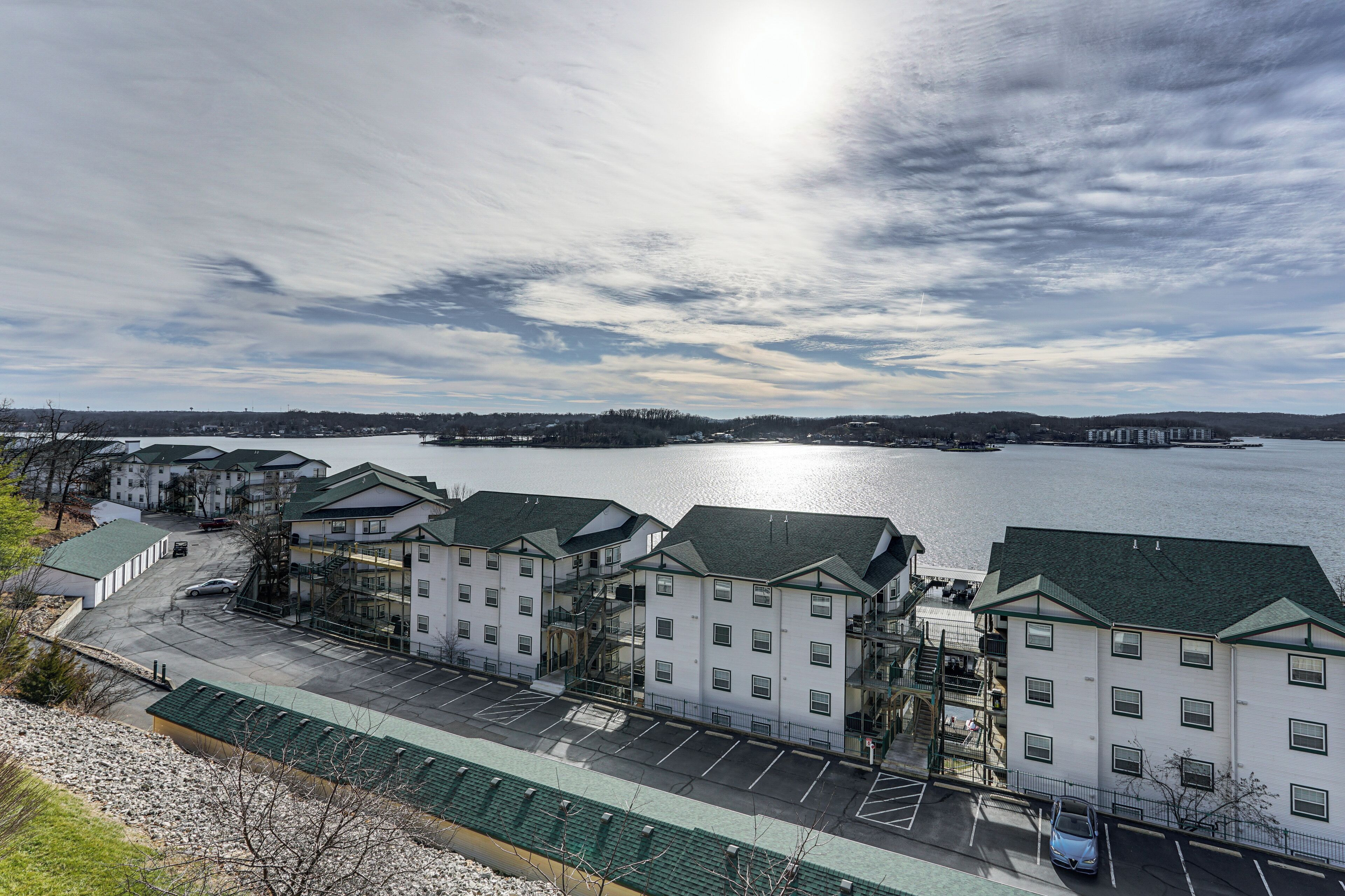Ein Hotel am Wasserufer mit mehreren Gebäuden, einem Parkplatz und Blick auf den See.