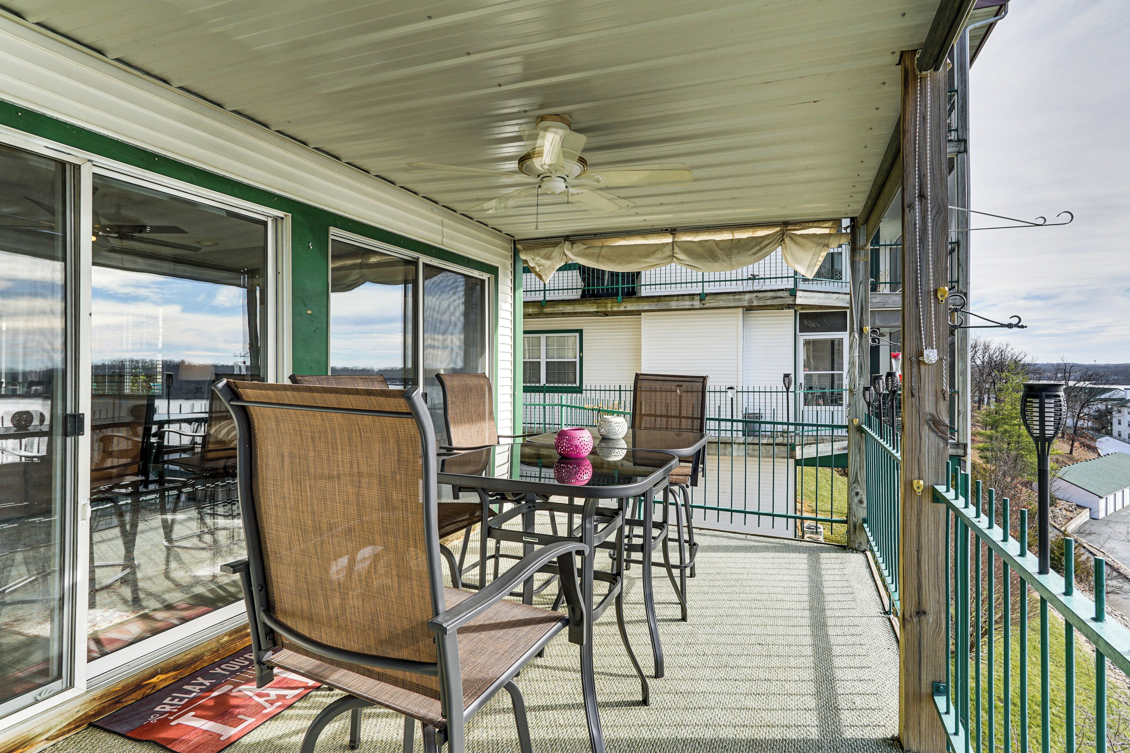 A covered outdoor patio with a table and chairs, a ceiling fan, and a view of the city.