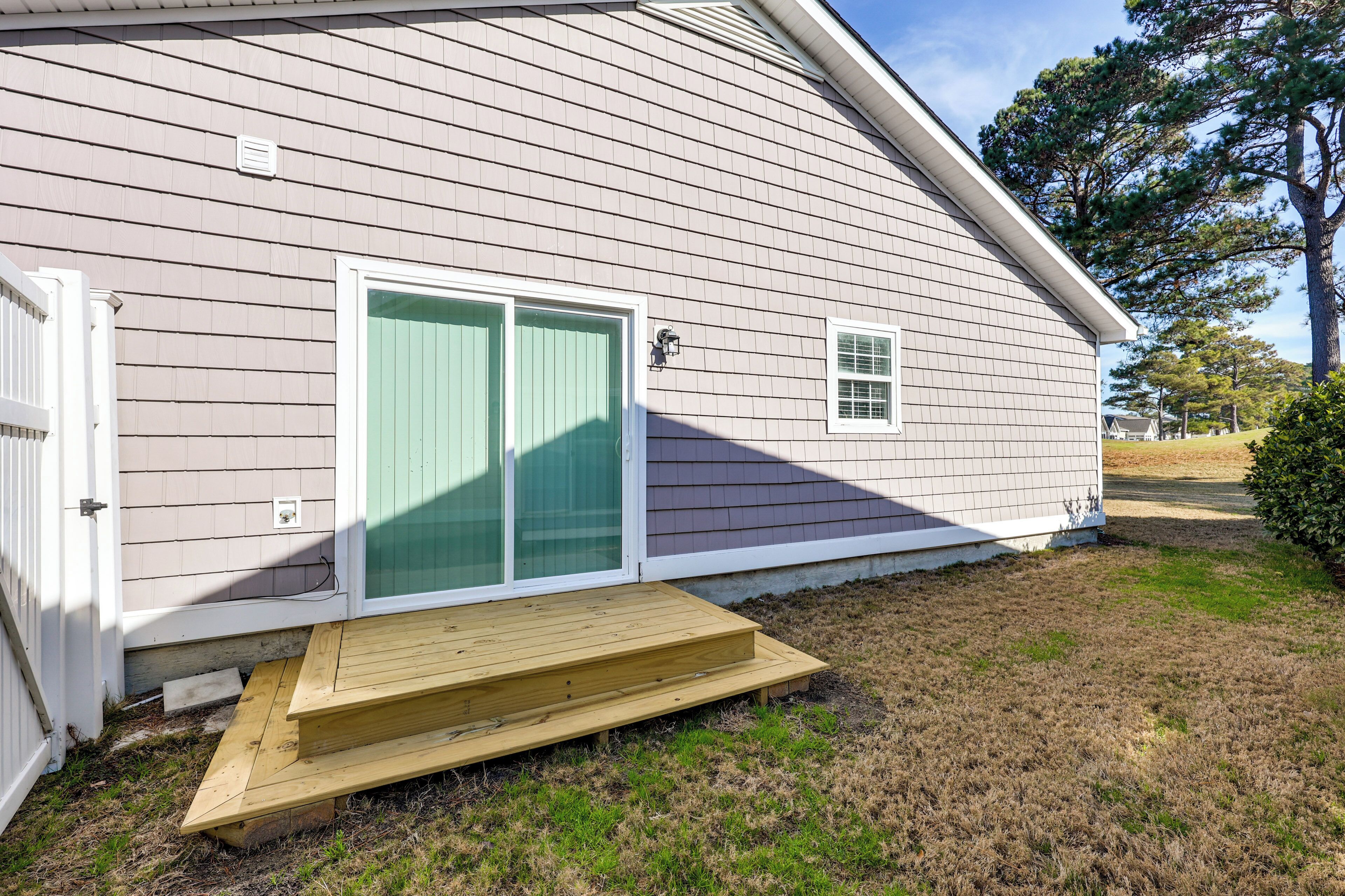A single-story house with a front porch, a sliding glass door, and a small window.