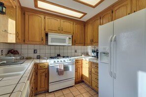 Une cuisine avec des meubles de rangement en bois, une cuisinière blanche, un four à micro-ondes et un réfrigérateur.