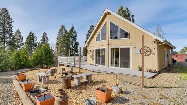 A two-story building with a sloped roof, large windows, and a paved patio area with outdoor seating. - Deck & Wooded Views: 5-acre Auberry Retreat! (Auberry)