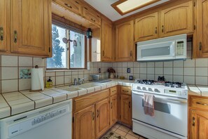Une cuisine avec des meubles de rangement en bois, un four à micro-ondes, une cuisinière et un lave-vaisselle.