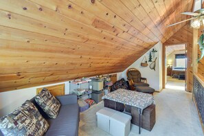 A cozy attic bedroom with a sloped ceiling, a bed, a sofa, and a small table. - Deck & Wooded Views: 5-acre Auberry Retreat! (Auberry)