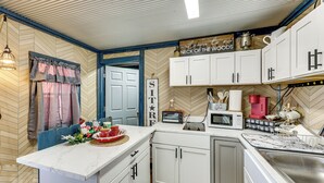A kitchen with white cabinets, a microwave, a toaster, and a coffee maker. There is a sign above the counter that reads "Welcome to Neck of the Woods." - Gym Access On-site: Cabin w/ Deck in Red Oak! (Red Oak)