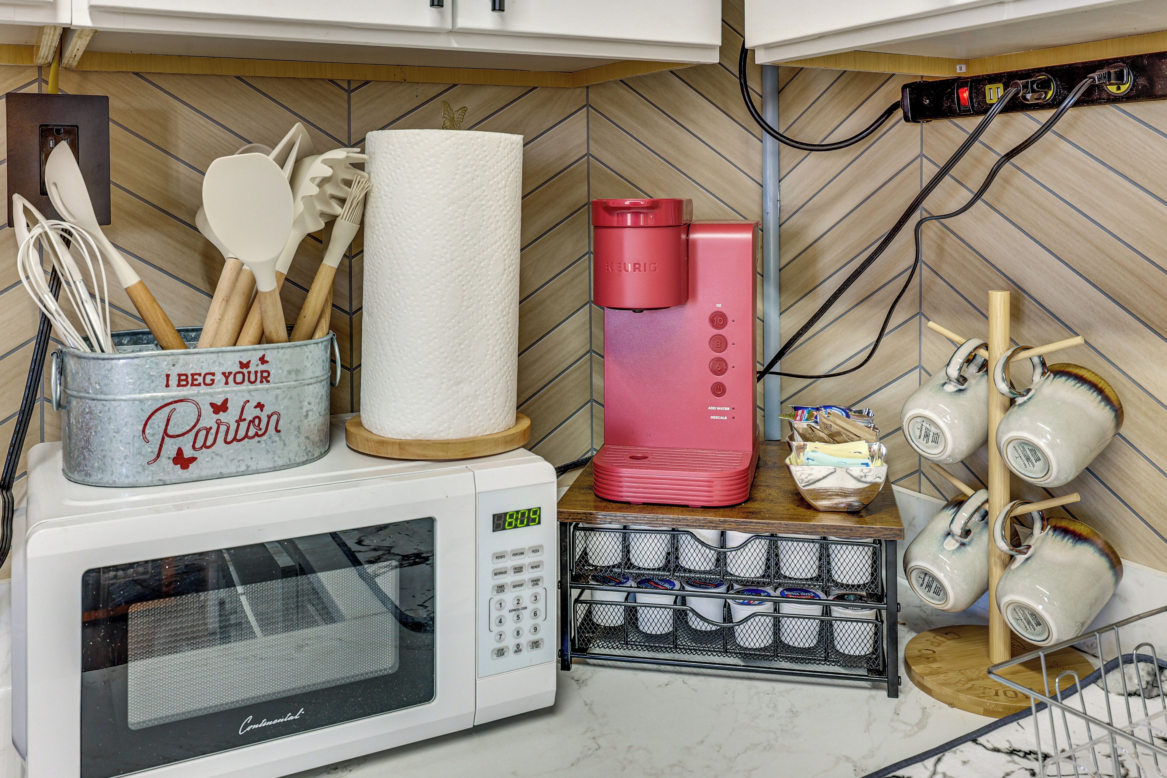 Une cuisine équipée d’un four à micro-ondes, d’un porte-essuie-tout, d’une machine à café et d’un porte-tasses.