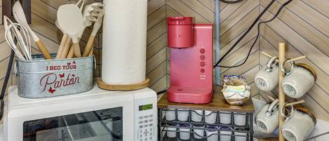 Une cuisine équipée d’un four à micro-ondes, d’un porte-essuie-tout, d’une machine à café et d’un porte-tasses.