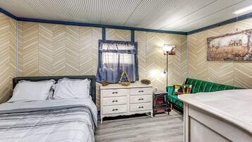 Un dormitorio con cama, cómoda y sofá verde.