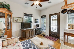 A living room with a television, wooden cabinets, a ceiling fan, and a door with decorative glass panels. - Work From Home: Peaceful Conroe Escape w/ Patio! (Conroe)