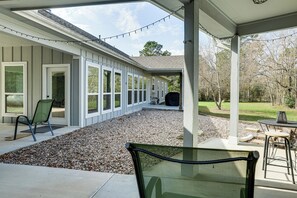A covered patio area with a gravel floor, a chair, a table, and string lights. - Work From Home: Peaceful Conroe Escape w/ Patio! (Conroe)