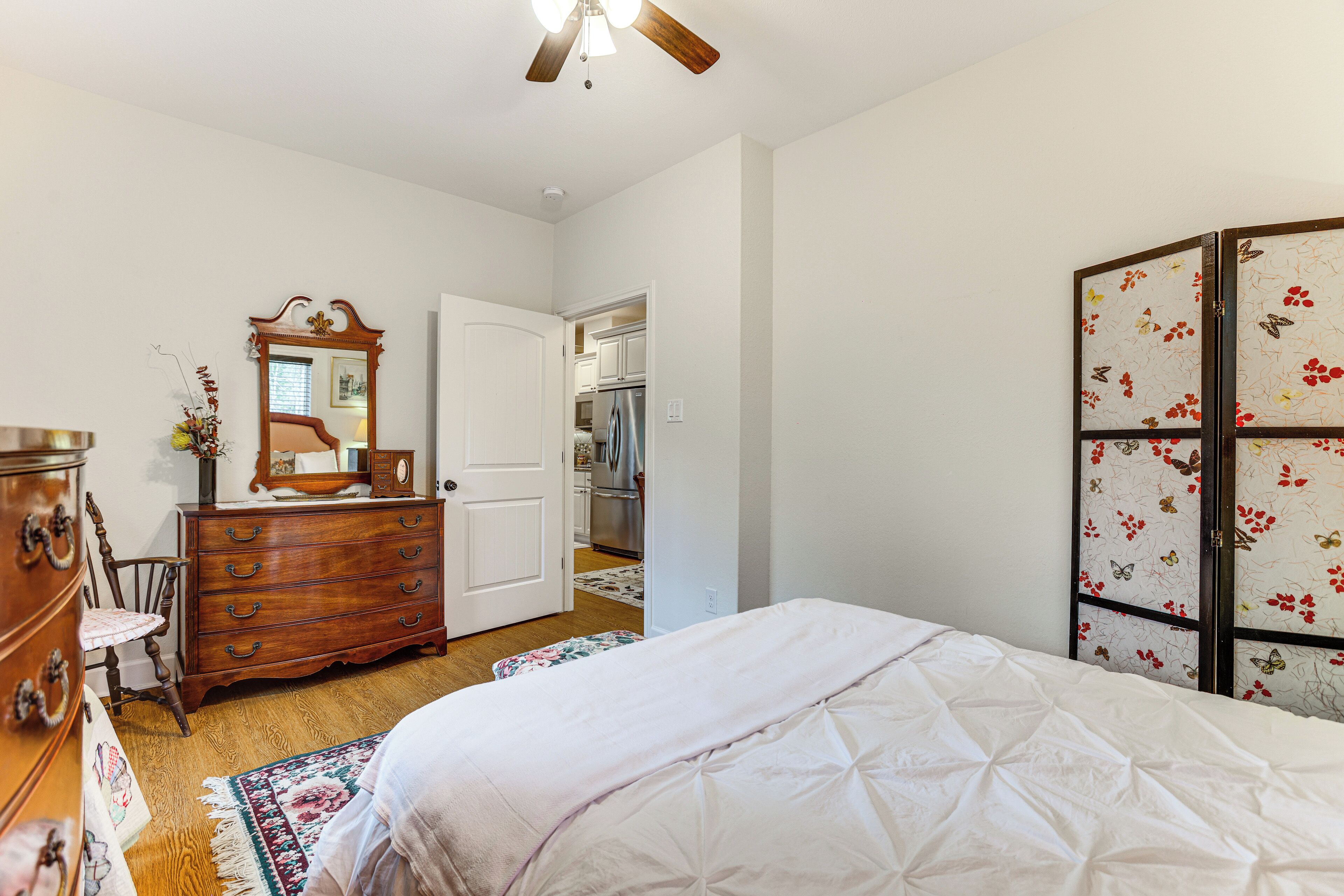 A bedroom with a bed, dresser, mirror, and a wardrobe with floral patterns.