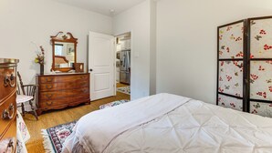 Une chambre à coucher comprenant un lit, une commode, un miroir et une armoire ornée de motifs floraux.