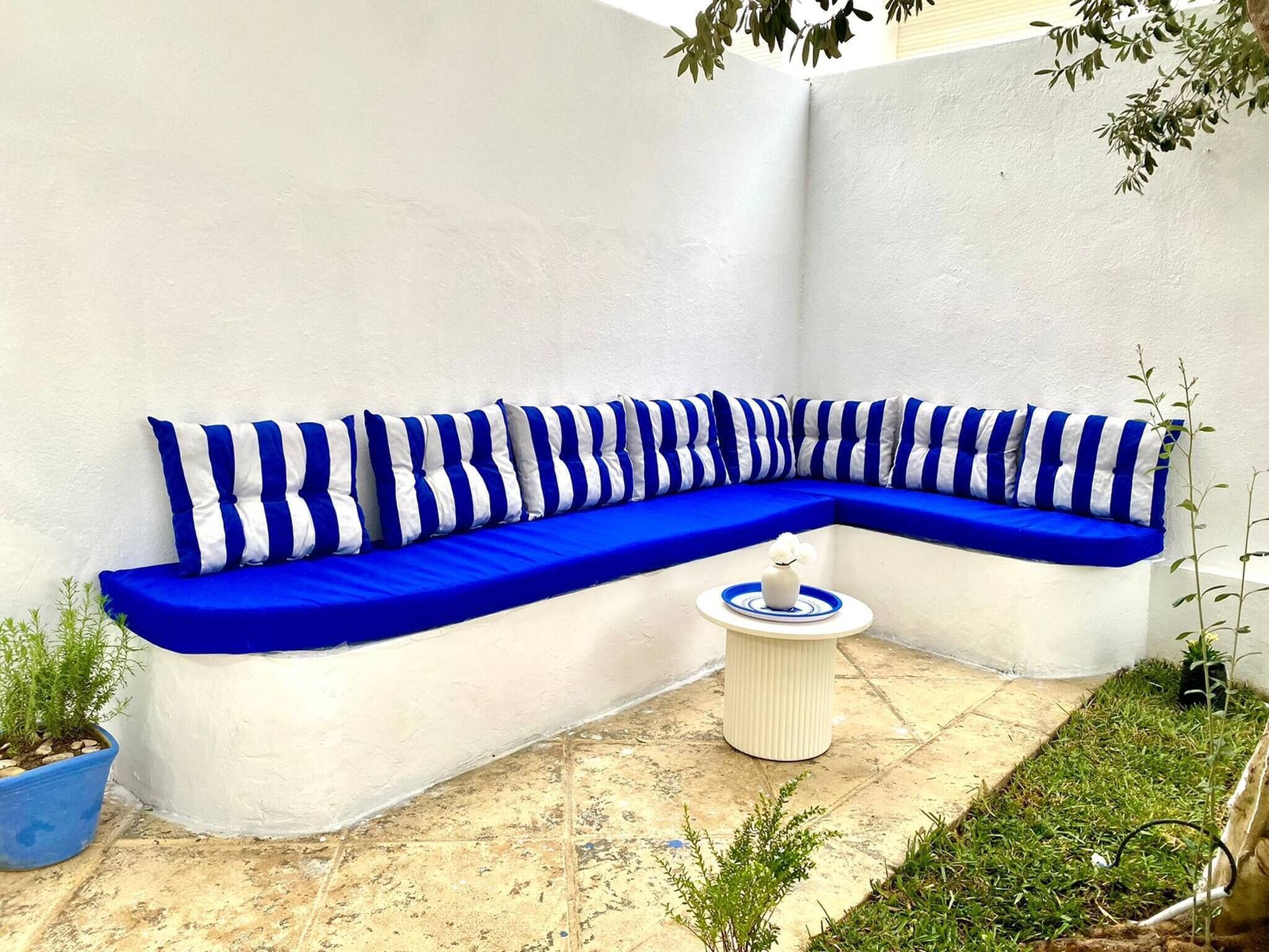A corner seating area with a blue and white striped sofa, a small round table, and a potted plant.