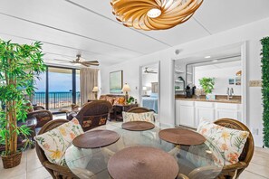 A spacious living area with a glass table, wicker chairs, and a view of the ocean. - 2BR w/ Gulf-view Balcony: Suntide III - Unit 404 (South Padre Island)