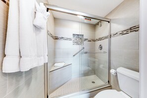 Une salle de bain moderne avec une douche à parois de verre, des toilettes et un porte-serviettes.