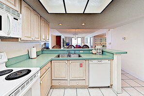 Une cuisine dotée d’un îlot central, d’un four à micro-ondes, d’une cuisinière et d’un lave-vaisselle.