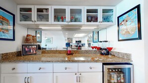 A kitchen with white cabinets, a granite countertop, and a refrigerator. - 3BR Gulf-view Suite w/ Pools, Gym & Tennis (South Padre Island)