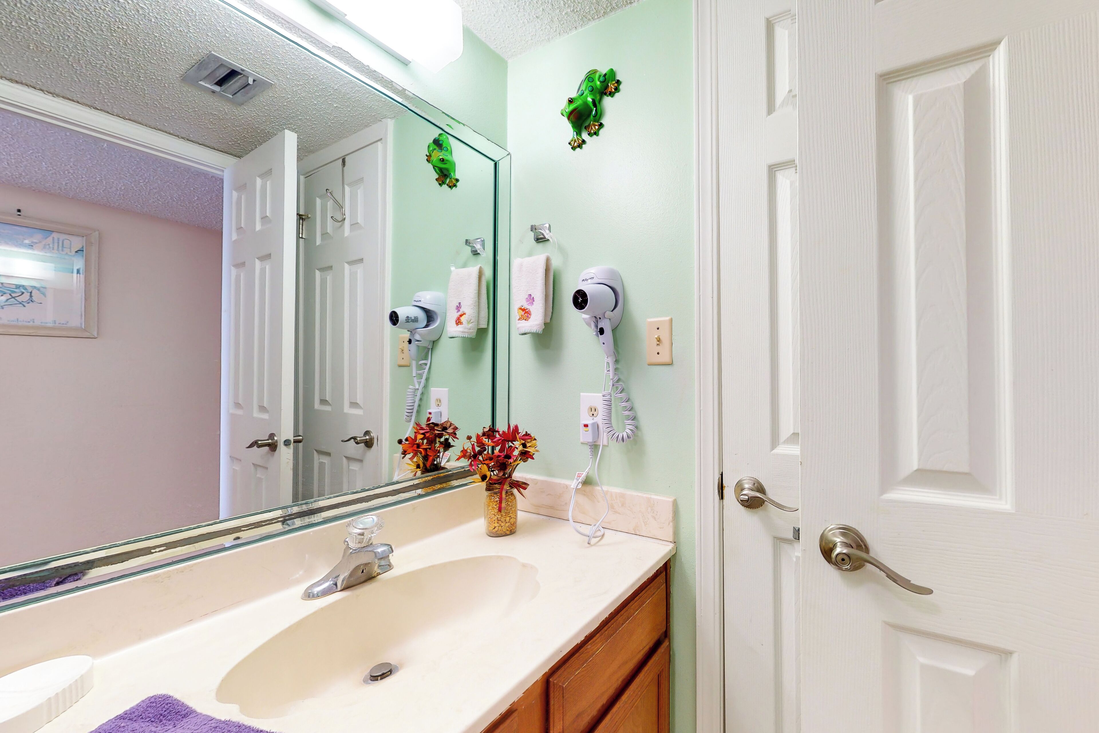 A bathroom with a sink, mirror, towel rack, and a door with a frosted glass panel.