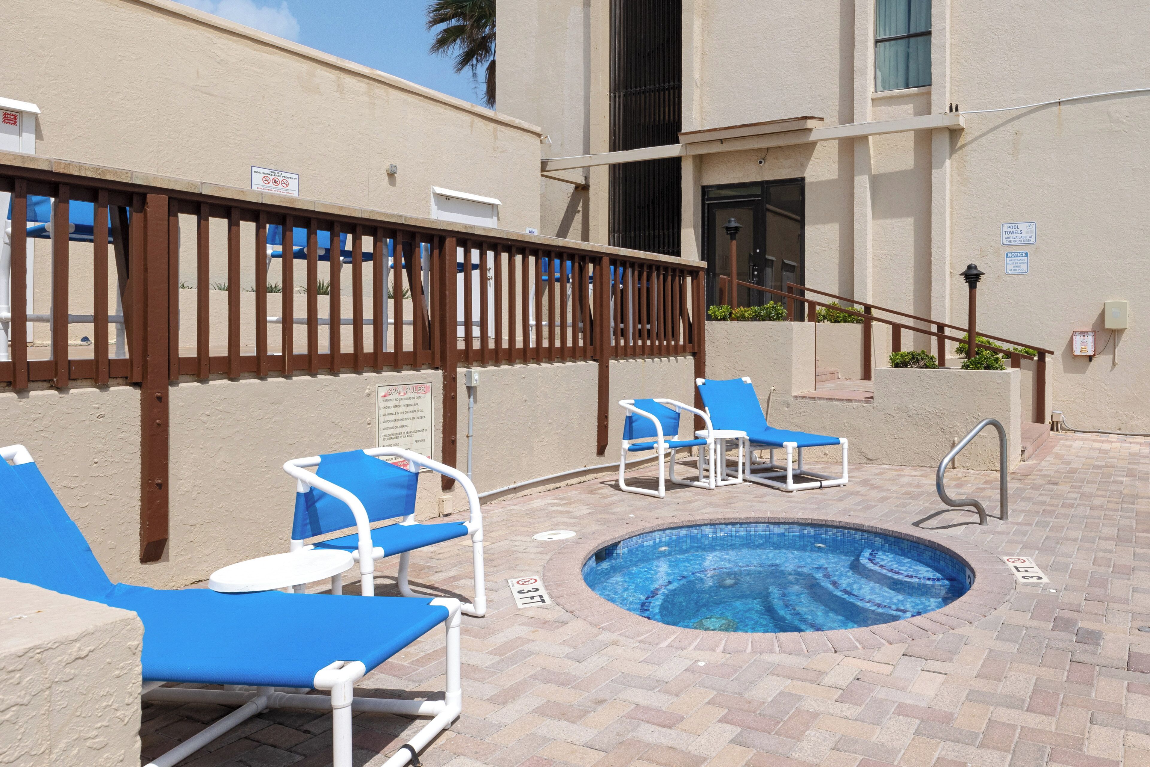 A pool area with lounge chairs and a wooden fence.