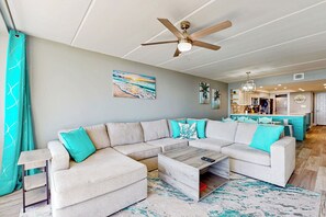 A modern living room with a sectional sofa, a coffee table, and a ceiling fan. - All-suite 2BR w/ Gulf-view: Suntide III - Unit 407 (South Padre Island)