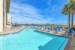 A swimming pool with blue lounge chairs and palm trees. - Resort Perks & Gulf Views: Suntide III - Unit 304 (South Padre Island)