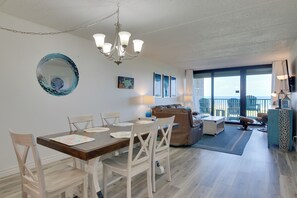 Ein geräumiger Wohnbereich mit Esstisch, Stühlen, einer Couch und einem Balkon mit Blick.