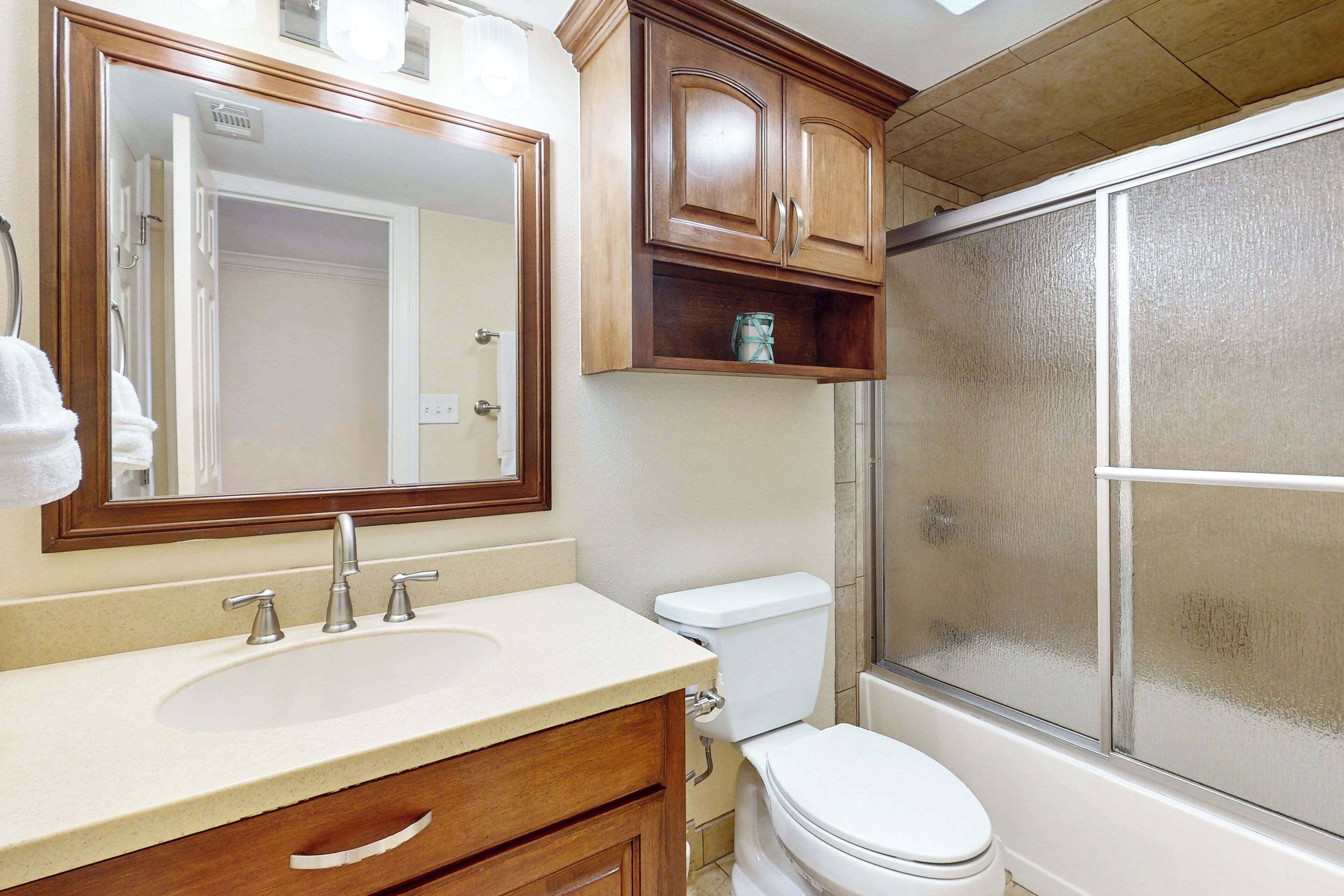 Ein Badezimmer mit Waschbecken, Spiegel, Schrank, Toilette und Dusche.