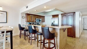 A modern kitchen with a central island, bar stools, and built-in appliances. - 3BR Gulf-view Resort Condo: Suntide III - Unit 605 (South Padre Island)