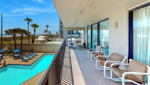 Ein Balkon mit Pool, Liegestühlen und Blick auf Strand und Meer.