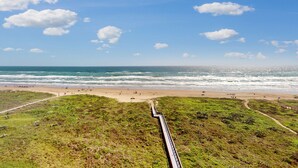 Un paysage côtier avec une plage, l’océan et un sentier menant au rivage.