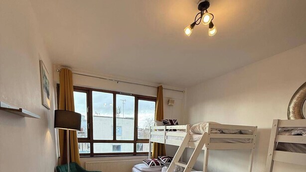 A room with a bunk bed, a desk, a chair, and a window with curtains. - Modern Bright Top-floor Flat (London)