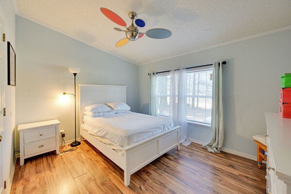 A bedroom with a bed, bedside table, floor lamp, ceiling fan, and a window with curtains. - 9 Mi to Ecu: Pet-friendly Greenville Home w/ Deck (Greenville)