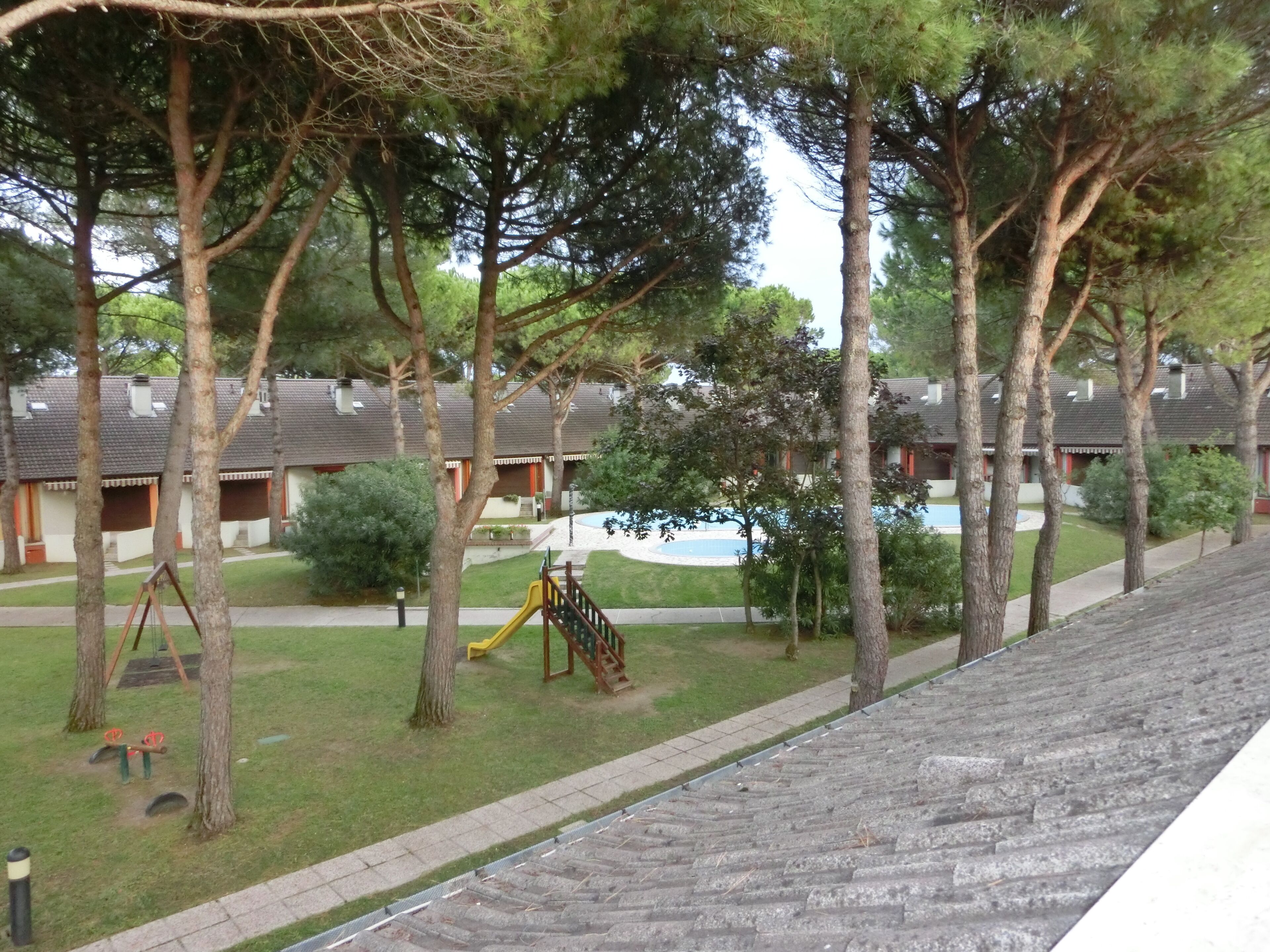 Et boligområde med legeplads, træer og huse med saddeltage.