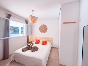 A bedroom with a bed, a window, a wall-mounted light fixture, and a decorative wall piece. - Les Oliviers Villa with a Rooftop Terrace (Prunelli-di-Fiumorbo)