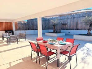 A covered outdoor dining area with a table set for six, surrounded by red chairs. - Les Oliviers Villa with a Rooftop Terrace (Prunelli-di-Fiumorbo)