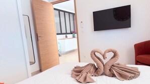 Ein Hotelzimmer mit Bett, Fernseher an der Wand und einer Tür zu einem Balkon.