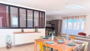 Ein Essbereich mit einem Holztisch, bunten Stühlen und einer Küche im Hintergrund.
