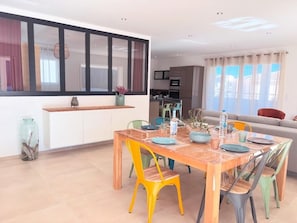 A dining area with a wooden table, colorful chairs, and a kitchen in the background. - Rooftop villa les oliviers (Prunelli-di-Fiumorbo)