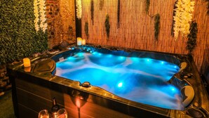 A hot tub with a wooden bench and candles, surrounded by greenery and decorative flowers. - La Villa Lova - Loveroom with private spa in Pamiers (Pamiers)