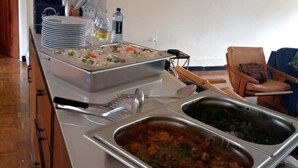 Un buffet con diversi piatti, tra cui riso e un contorno di verdure, in una stanza con pavimento in legno e un quadro appeso al muro.